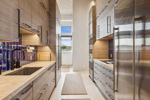 Kitchen with stainless steel built in fridge, tasteful backsplash, modern cabinets, and light countertops