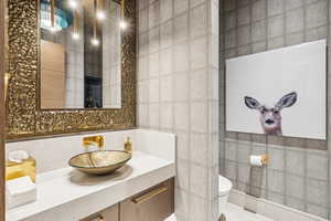 Bathroom featuring tile walls, vanity, and decorative backsplash