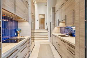 Kitchen with modern cabinets, tasteful backsplash, a towering ceiling, light brown cabinets, and light tile patterned flooring