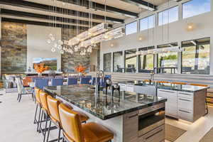 Bar featuring a towering ceiling, beamed ceiling, pendant lighting, light tile patterned floors, and a chandelier