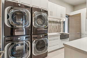 Washroom featuring stacked washer and clothes dryer, washer and clothes dryer, and cabinet space