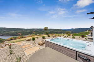 View of pool with a hot tub and a water and mountain view