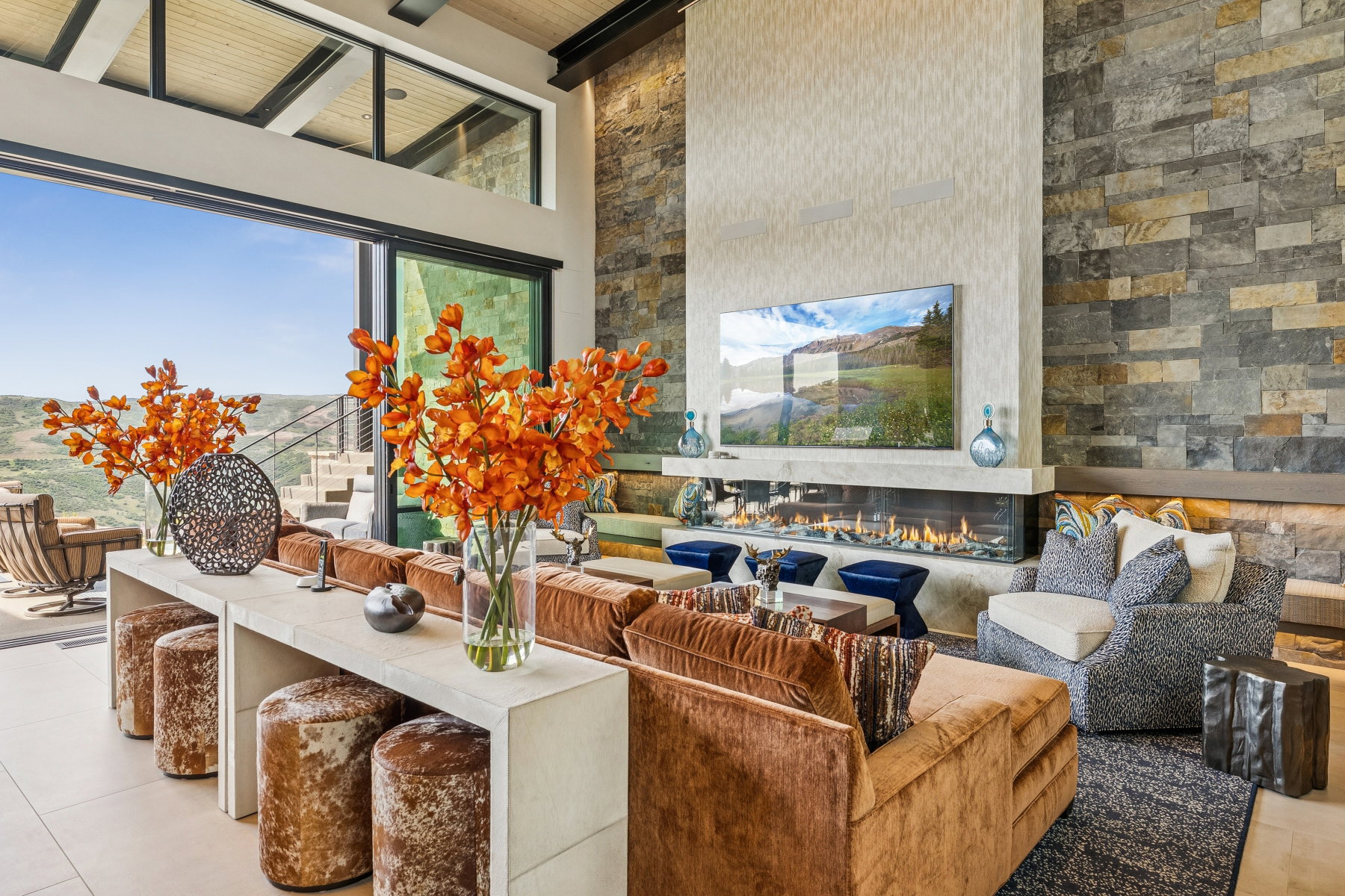 Tiled living area featuring a towering ceiling, a glass covered fireplace, and a wood ceiling with exposed beams