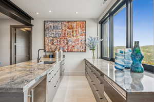 Kitchen featuring beverage cooler, recessed lighting, light stone counters, white cabinets, and a peninsula