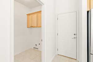 Laundry area with light tile patterned floors and cabinet space