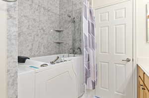 Bathroom featuring washer / dryer, vanity, and shower / bath combo