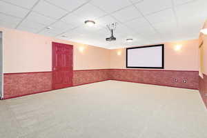 Cinema room with wainscoting, a drop ceiling, and carpet flooring