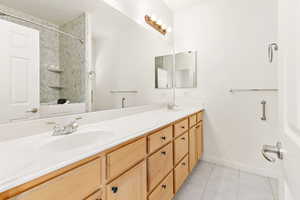 Bathroom with tile patterned floors, double vanity, and shower / bathtub combination