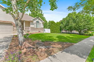 View of home's exterior with stucco siding, stone siding, a yard, a garage, and roof with shingles