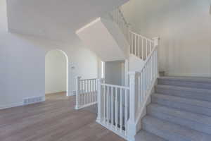 Stairway with wood finished floors and arched walkways