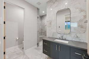 Bathroom featuring a stall shower, vanity, and marble finish floors