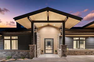 Exterior entry at dusk with stone siding and a porch