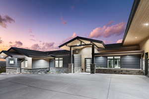 View of front of home featuring stone siding and curved driveway