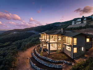 View of side of property featuring a balcony, stone siding, roof mounted solar panels, and a chimney