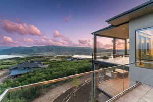 Balcony at dusk featuring a water and mountain view