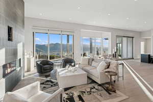 Living room featuring a tiled fireplace, healthy amount of natural light, light wood-style floors, recessed lighting, and a mountain view
