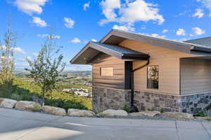 View of property exterior with stone siding and roof with shingles