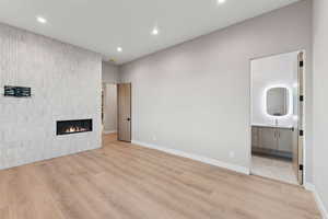 Unfurnished living room with light wood-type flooring, a tiled fireplace, and recessed lighting