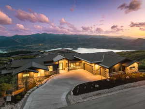 View of front of house with stone siding, a garage, curved driveway, and a mountain view