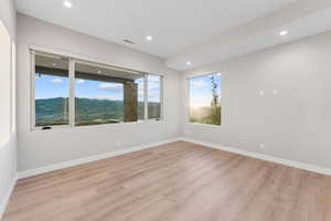 Empty room featuring light wood-style floors, a mountain view, and recessed lighting