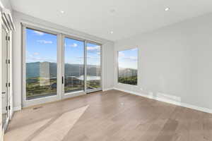 Empty room featuring light wood finished floors, a water and mountain view, and recessed lighting