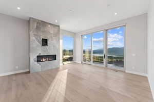 Unfurnished living room with light wood-style flooring, a tile fireplace, recessed lighting, and a water and mountain view