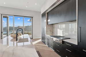 Kitchen with modern cabinets, light wood-style flooring, a mountain view, stainless steel gas cooktop, and backsplash
