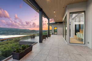 Patio terrace at dusk featuring a balcony and a mountain view