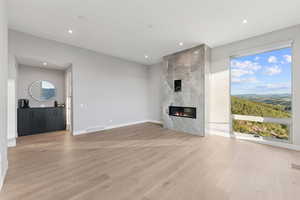 Unfurnished living room featuring light wood-style flooring, a premium fireplace, and recessed lighting