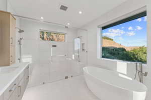 Bathroom featuring a soaking tub, a shower stall, vanity, tile walls, and recessed lighting
