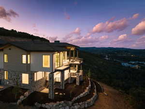 Back of property at dusk with a balcony and stucco siding