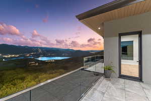 Balcony at dusk featuring a water and mountain view