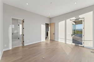 Unfurnished bedroom featuring access to outside, light wood finished floors, recessed lighting, and ensuite bathroom