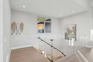 Staircase with wood finished floors and recessed lighting