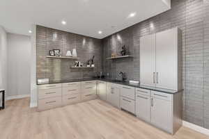 Indoor wet bar featuring light wood finished floors, recessed lighting, and tile walls