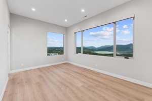 Empty room featuring a mountain view, light wood-style floors, and recessed lighting