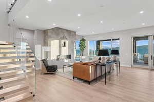 Living area featuring light wood-type flooring, a fireplace, stairs, and recessed lighting