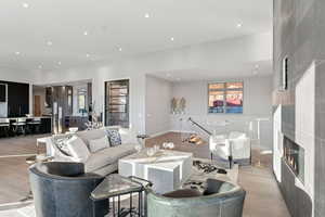 Living area with a large fireplace, light wood-type flooring, and recessed lighting