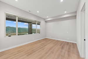 Empty room featuring a mountain view, light wood finished floors, and recessed lighting