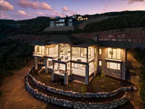 Rear view of house featuring a balcony and stone siding