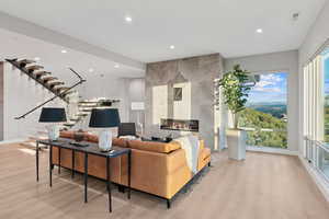 Living area with a tile fireplace, recessed lighting, stairs, and light wood-style flooring