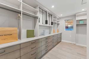 Walk in closet with light wood-style floors