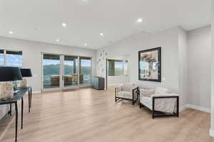 Living area with light wood finished floors and recessed lighting