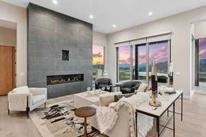 Living area featuring light wood-style flooring, recessed lighting, a tile fireplace, and a water and mountain view