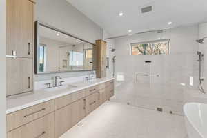 Bathroom with a shower stall, a freestanding tub, double vanity, recessed lighting, and tile patterned flooring