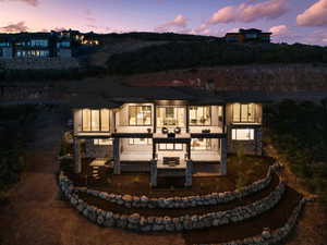 Back of property at dusk with stone siding and a patio