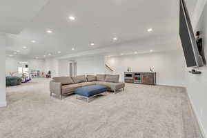 Carpeted living room featuring beverage cooler, bar with sink, recessed lighting, and stairs