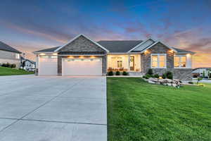 Craftsman house with stone siding, a lawn, a garage, and concrete driveway