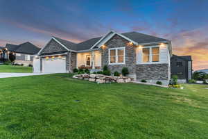 Craftsman inspired home with stone siding, a yard, a garage, and concrete driveway
