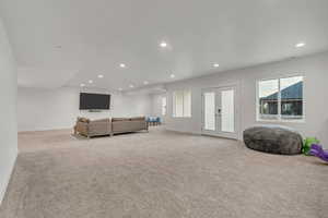 Carpeted living area with french doors and recessed lighting